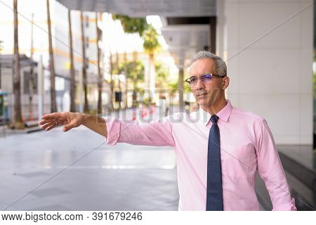 Handsome Persian Businessman Hailing Cab Outside Modern Building