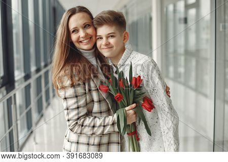Son Giving A Mother A Bunch Of Red Tulips In Amodern Hall