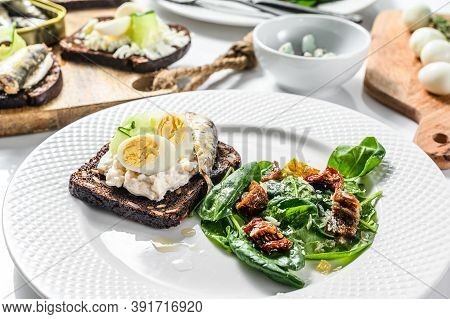 Delicious Appetizer Tapas, Soft Boiled Eggs And Canned Sardines Sandwiches. Salad With Spinach And D