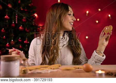 Traditionalist Concept. Cute Brunette Young Woman Making Christmas Gingerbread On Backdrop Of Christ