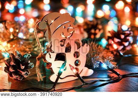 Christmas Background With Wooden Snowman Against The Backdrop Of Christmas Lights
