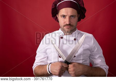 Unshaven Handsome Male Chef Cook Or Baker Man In Chefs Hat Posing Looking At Camera Isolated On Red 