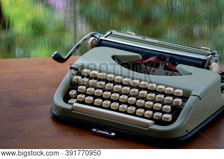 Vintage Retro Typewriter Sitting On Table Against A Rainy Window