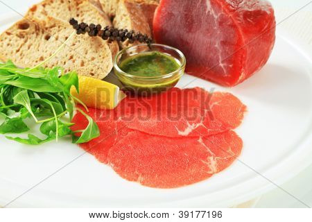 ingredienser för kallt kök bestående av rått kött, bröd, citron, peppar och pesto