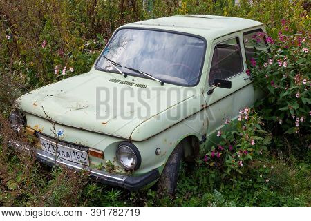 Novosibirsk, Russia - 09.19.2020: An Old Abandoned Car With Peeled Paint And Disassembled Parts Of T