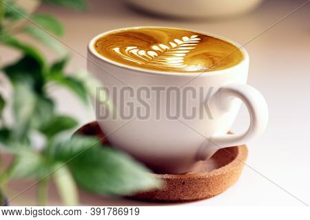 Latte Art Coffee In White Mug With White Background And Green Leaves