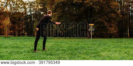 Young Caucasian Man Playing Disc Golf On Autumn Play Course With Basket