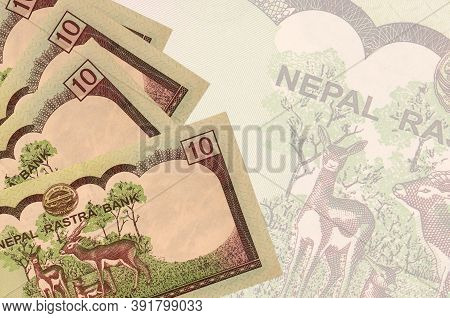 10 Nepalese Rupees Bills Lies In Stack On Background Of Big Semi-transparent Banknote. Abstract Busi
