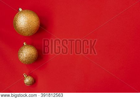 Three Golden Christmas Balls Of Different Sizes Are Displayed In A Row As A Border On A Red Backgrou