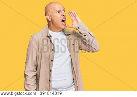 Middle age bald man wearing casual clothes shouting and screaming loud to side with hand on mouth. communication concept. 