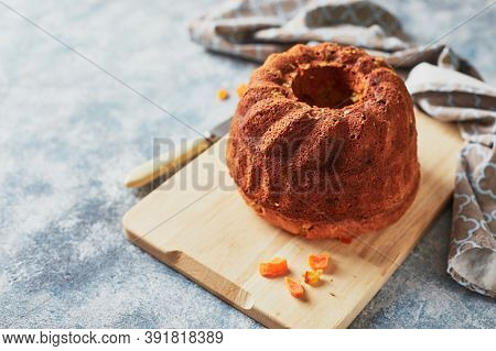 Homemade Autumn Carrot Cake With Candied Fruits On Wooden Cutting Board On Blue Background
