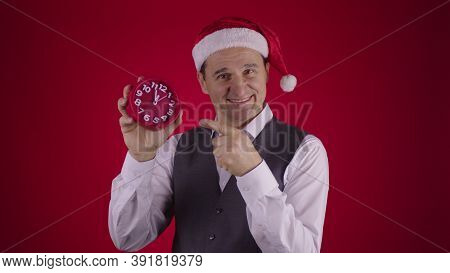 Cheerful 40s Man In Santa Hat Joyfully Pointing At Alarm Clock, Reminds Minutes Before Midnight At N