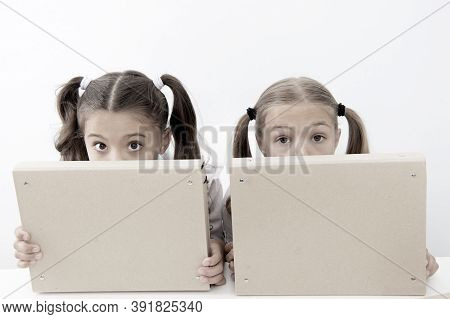 Little Awkward Girls Hide Faces Behind File Folders. Little Awkward Girls Enjoy Playing Together.