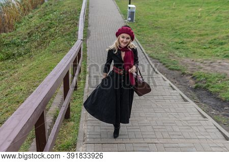 A Beautiful Woman Walks Up The Stairs And In Burgundy Pall And Biret, An Adult With A Beautiful Smil