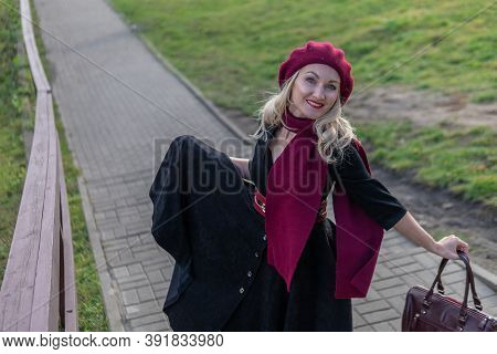 A Girl Walks Up The Stairs And In A Burgundy Palette And Biret, An Adult Smiles At The Camera In Bla