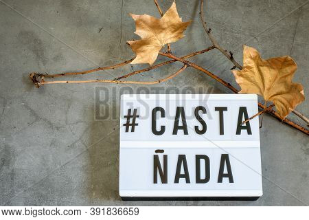 Dark Halloween Background With Dry Tree Branches And Golden Decorative Leaves, Text Castañada.