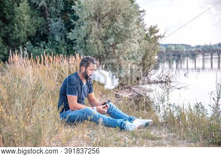 Stylish Man Smokes E-cigarette Exhales Smoke. Man Really Likes Process Of Smoking.
