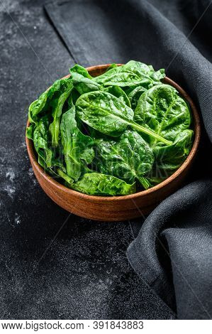 Young Raw Spinach In A Wooden Bowl. Black Background. Top View