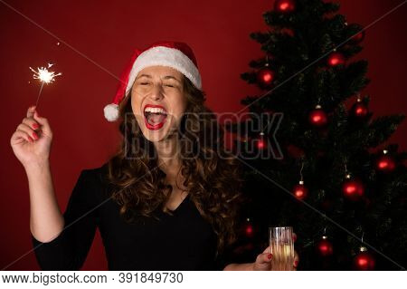 Beautiful Long-hair Brunette Girl In Santa Claus Hat Fun Singing Holiday Songs With Burning Sparkler