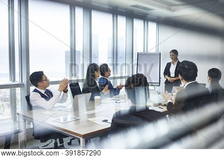 Asian New Employee Introducing Self During Staff Meeting In Conference Room