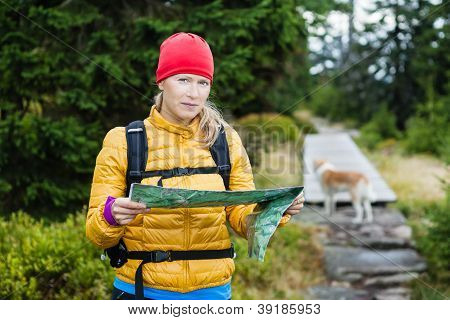 Woman Hiking And Reading Map In Forest