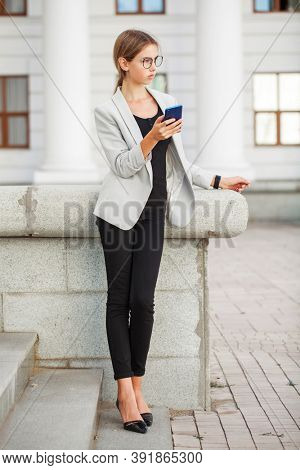 Full length portrait of a young beautiful girl in a gray jacket and black jeans