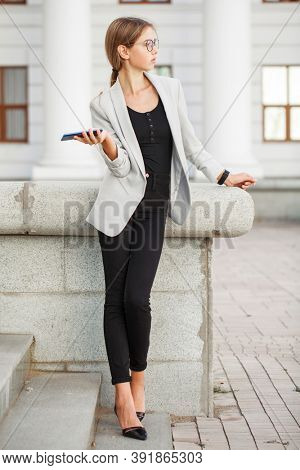 Full length portrait of a young beautiful girl in a gray jacket and black jeans