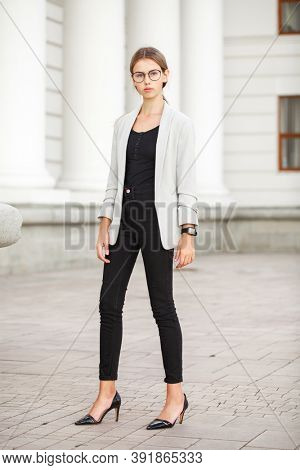 Full length portrait of a young beautiful girl in a gray jacket and black jeans