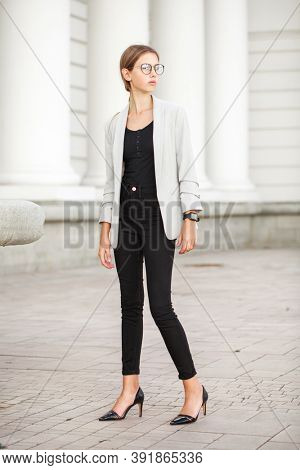 Full length portrait of a young beautiful girl in a gray jacket and black jeans