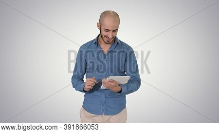 Arabian Man Walking And Using Tablet Surfing Internet On Gradien