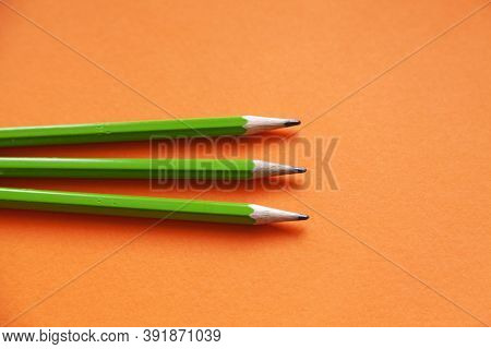 Three Green Pencils On An Orange Background