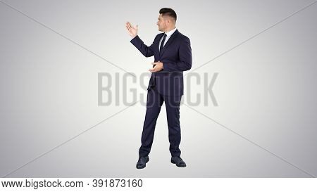 Smiling Businessman Pointing On Something And Talknig On Gradien