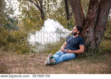 Bearded Smoker Enjoying An Vape In The Fresh Air. The New Technology Cigarette.