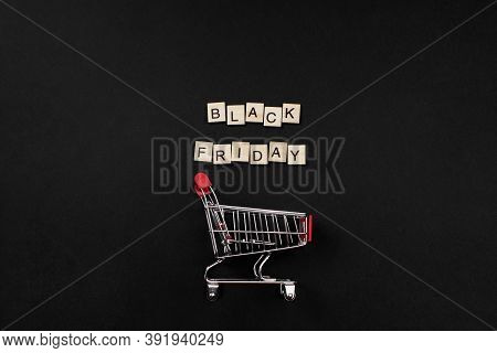 Black Friday Phrase Made Of Wooden Blocks And Shopping Cart Flat Lay On Black Background Top View. A