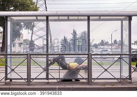 Woman With Briard Lies On Bench Of Public Transport Stop.