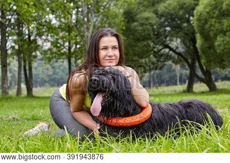 Briard Is Hugged By Female Owner On Grass In Park.