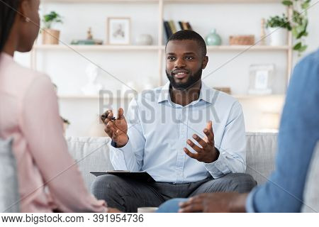 Marital Therapy. Black Man Professional Psychologist Consulting Married Couple On Meeting At His Off