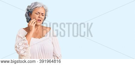 Senior woman with gray hair wearing bohemian style touching mouth with hand with painful expression because of toothache or dental illness on teeth. dentist 