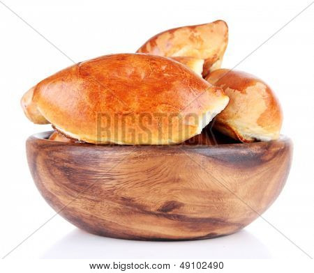 Empanadillas al horno frescas en un recipiente de madera, aislados en blanco