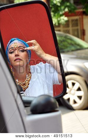 Senior Woman With Indian Jewlery Looking At Car Mirrow In The Street
