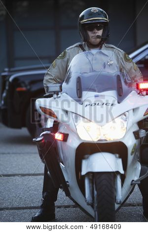 Longitud total de media de edad policía llevaba casco mientras está sentado en la moto