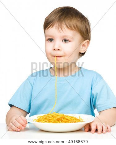 Little boy è succhiare un filamento singolo spaghetti, isolato su bianco