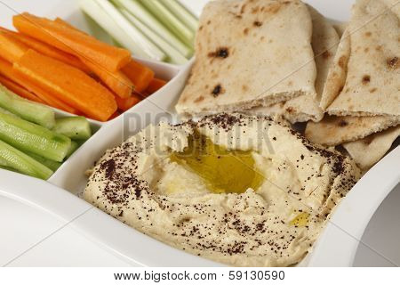 A dip tray with hummus, bread, carrot sticks, celery and cucumber.