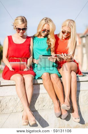 holidays and tourism concept - beautiful blonde girls toursits looking into tablet pcs in the city