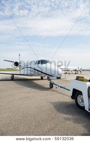 Private jet being towed by an airport vehicle