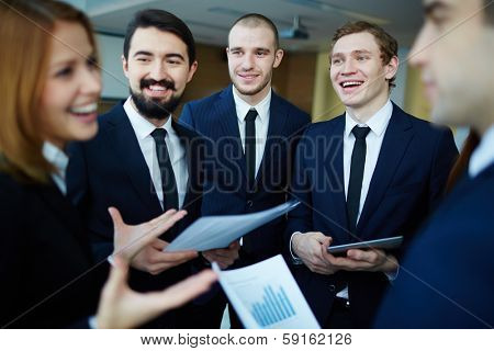 Group of business partners listening to their female co-worker explaining ideas at meeting