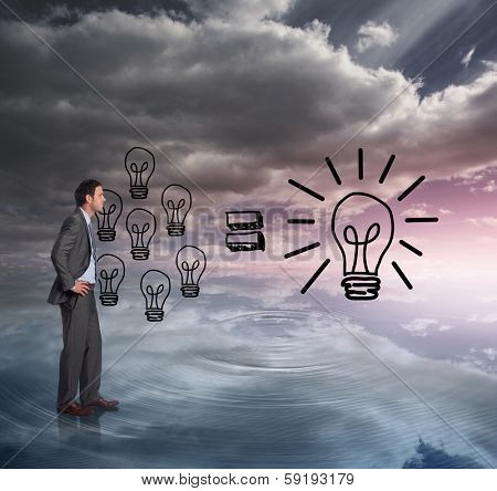 Smiling businessman with hands on hips against light bulbs graphic on colourful horizon
