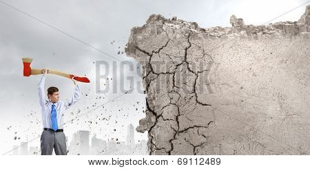 Young determined businessman with big axe in hands