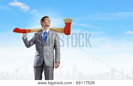 Young businessman holding big axe on shoulder