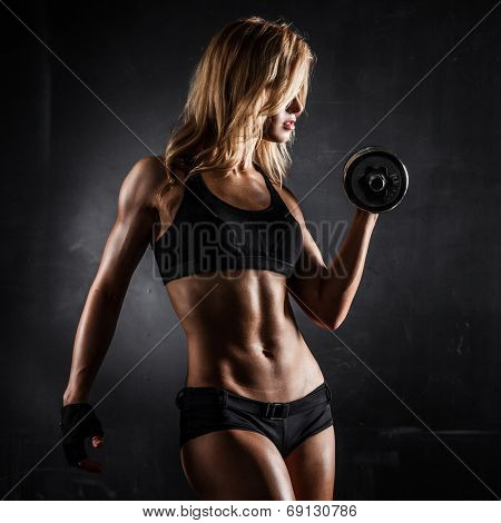 Brutal athletic woman pumping up muscles with dumbbells